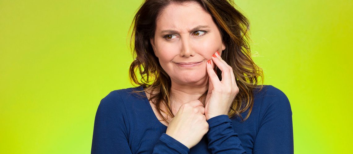 Portrait middle aged woman with sensitive tooth ache, crown problem crying from pain, touching outside mouth with hand isolated green background. Negative emotion, facial expression feeling, health
